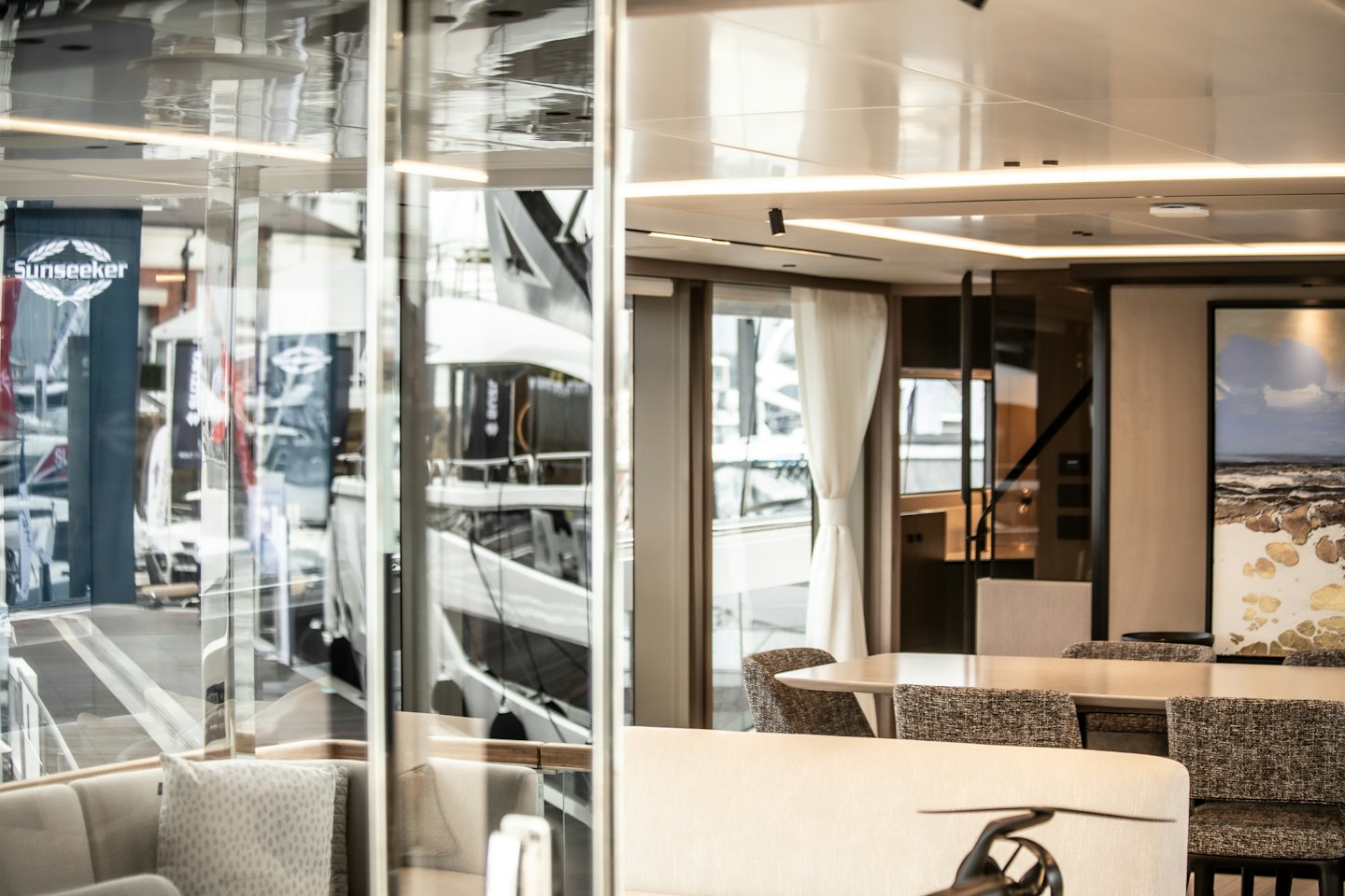 Interno di uno yacht moderno con divani chiari e zona pranzo.