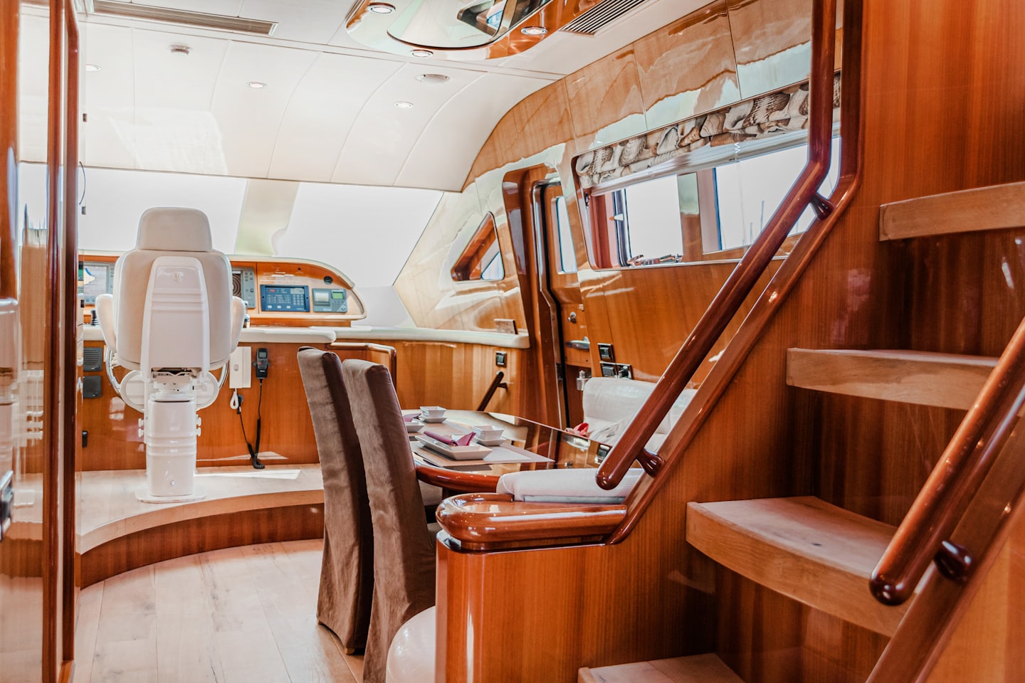 Postazione di comando di uno yacht con poltrona del capitano e zona pranzo.